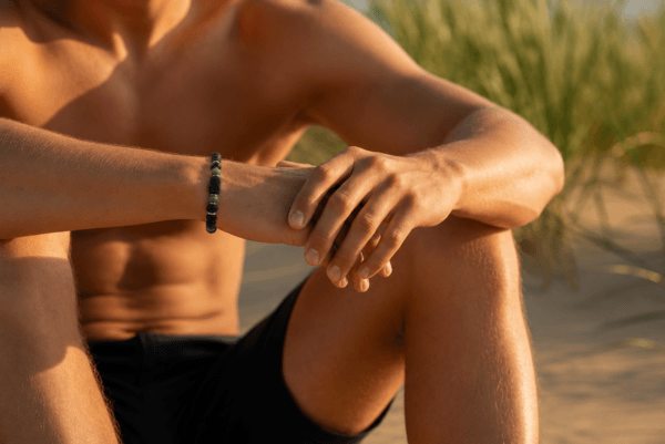 B021 na modelu — Bransoletka z Turmalinem, Rubinem w Zoizycie, Lawą Wulkaniczną i Onyksem Bransoletka z naturalnego turmalinu, rubinu w zoizycie, lawy wulkanicznej i onyksu prezentowana na męskim nadgarstku.