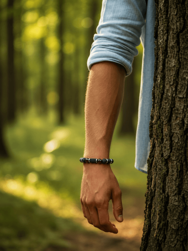 B059 na modelu — Bransoletka z Turmalinem, Granatem, Lawą Wulkaniczną i Hematytem Bransoletka z naturalnego turmalinu, granatu o burgundowym odcieniu, lawy wulkanicznej i hematytu prezentowana na męskim nadgarstku.